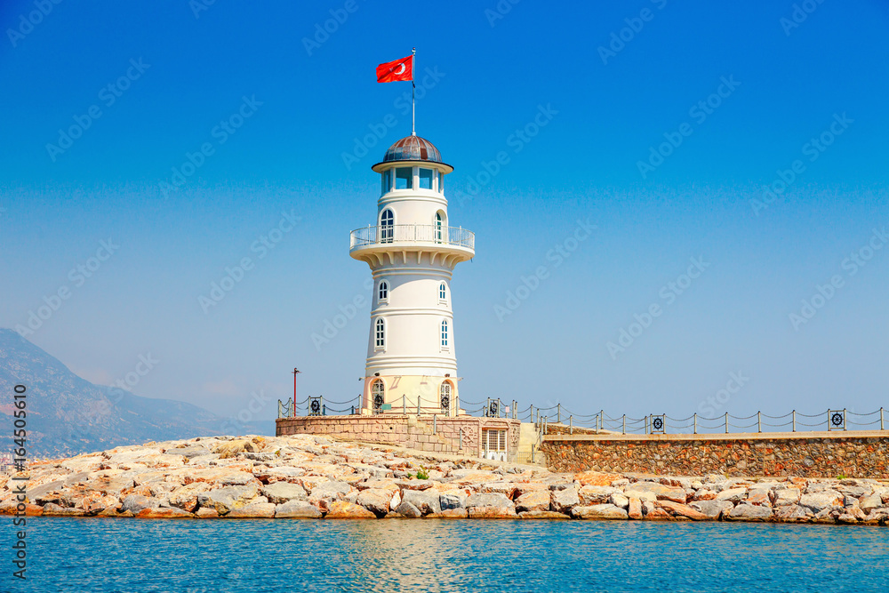 Lighthouse in Alanya, Antalya district, Turkey, Asia. View on city from boat. Popular tourist destination. Clear water in sunny day.