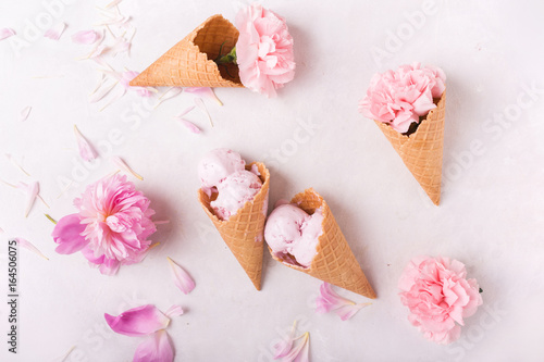 Ice cream in a waffle cone on a light background. Strawberry ice cream. Flowers in a waffle cone. Pink carnations. Flowers on a wooden background. Copyspace. Flower photo concept.