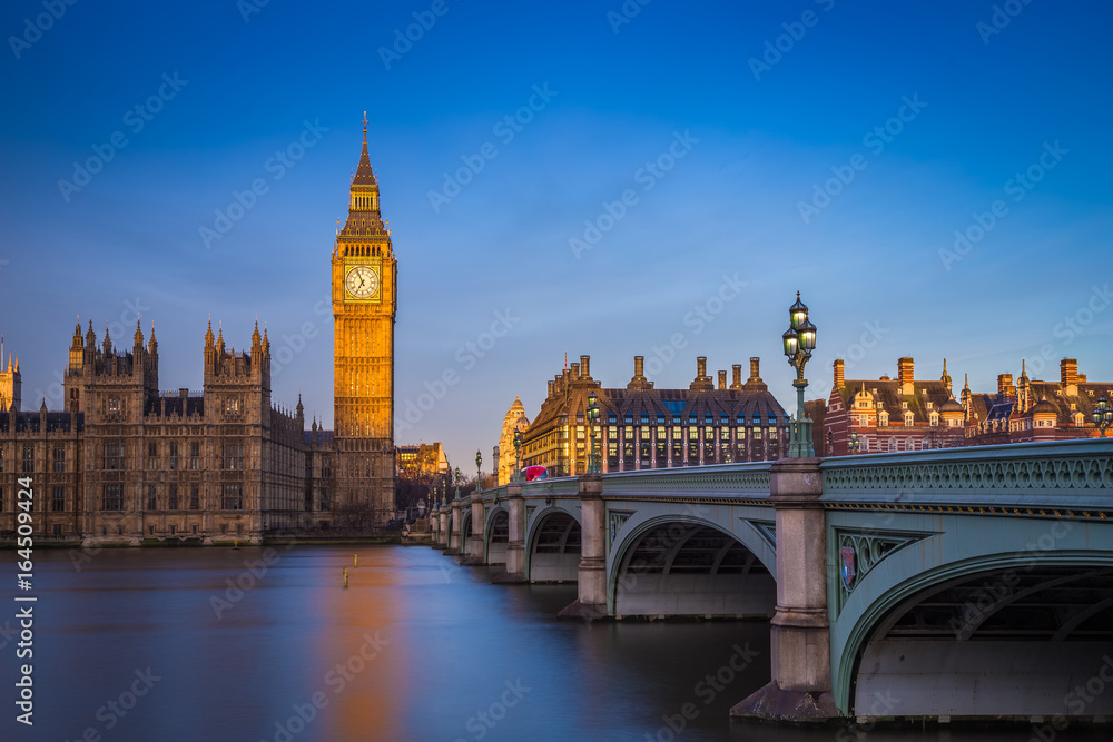 London, England - The beautiful Big Ben and Houses of Parliament at sunrise with clear blue sky and red double decker bus