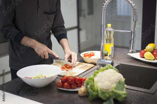 Man preparing vegetable salad in a modern kitchen