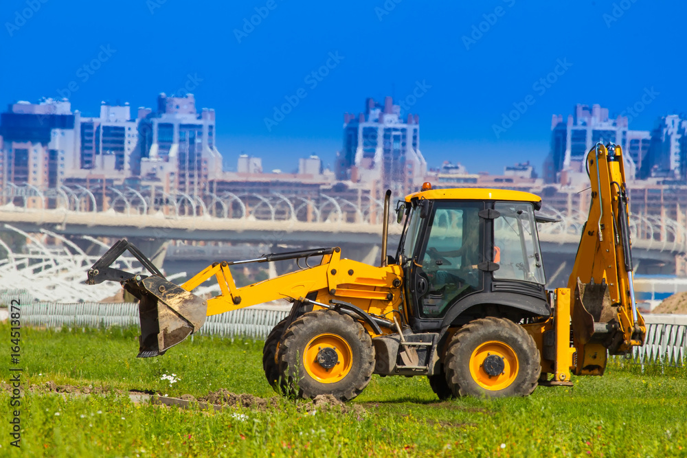 Tractor with a bucket. Tractor on the background buildings. Tractor with a bucket. Tractor on the background buildings.