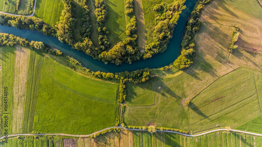 River bend surrounded by fields from bird's eye view.