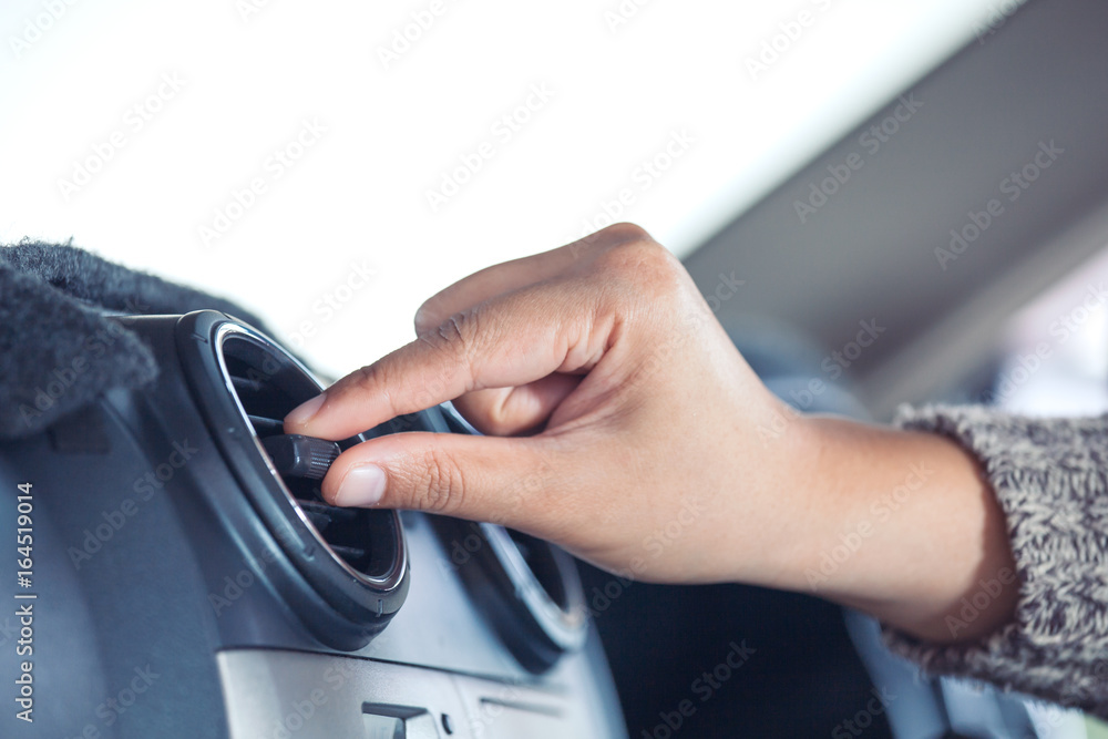 Fototapeta premium Woman hand adjusting car air conditioning system grid panel in vintage color tone