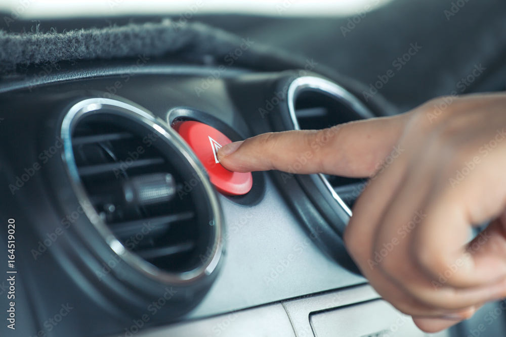 Woman finger pressing emergency button on car dashboard in vintage color tone