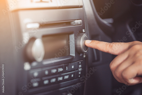 Woman hand turn on the radio while driving a car in vintage color tone
