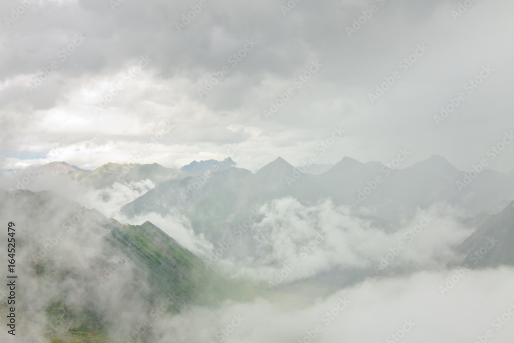 Peaks of rocky mountains in clouds and fog