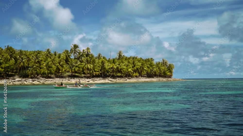 White outrigger boat sailing in front of tropical island with palm trees, Philippines White outrigger boat sailing in front of tropical island with palm trees, Philippines