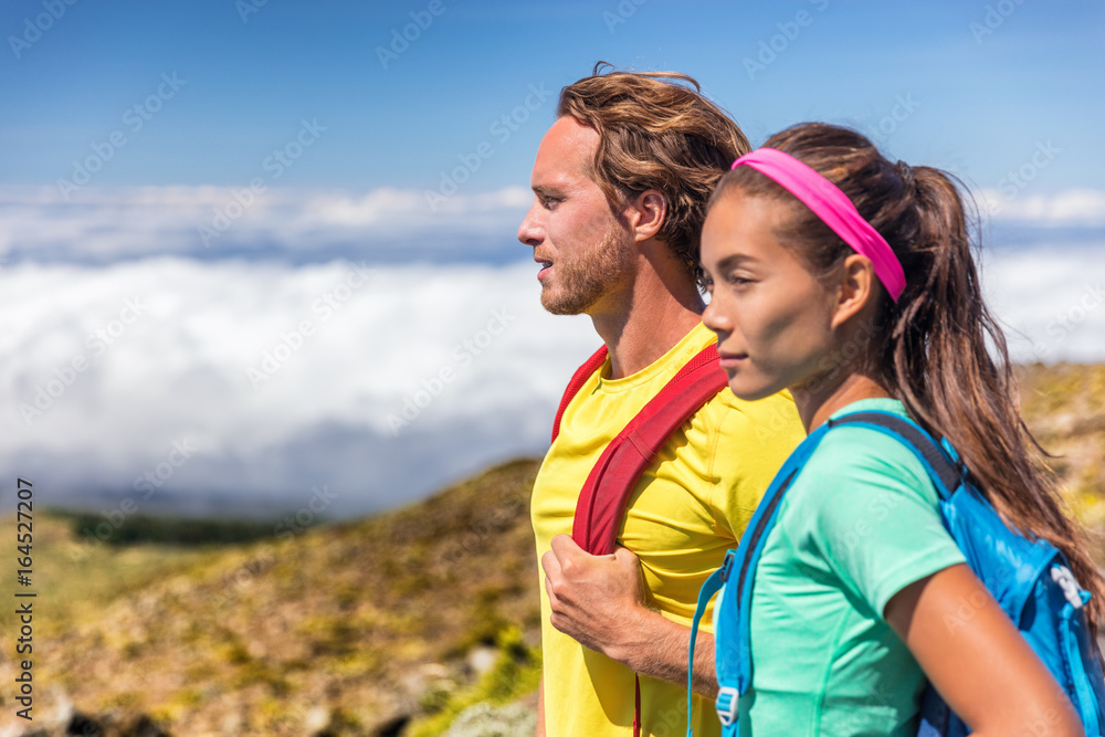 Couple hikers hiking in mountain nature landscape. Healthy active people lifestyle in summer outdoors backpacking with bags on trail walk.