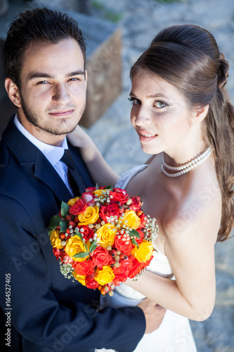 Wife and groom in wedding day looking up at the camera. Just married couple