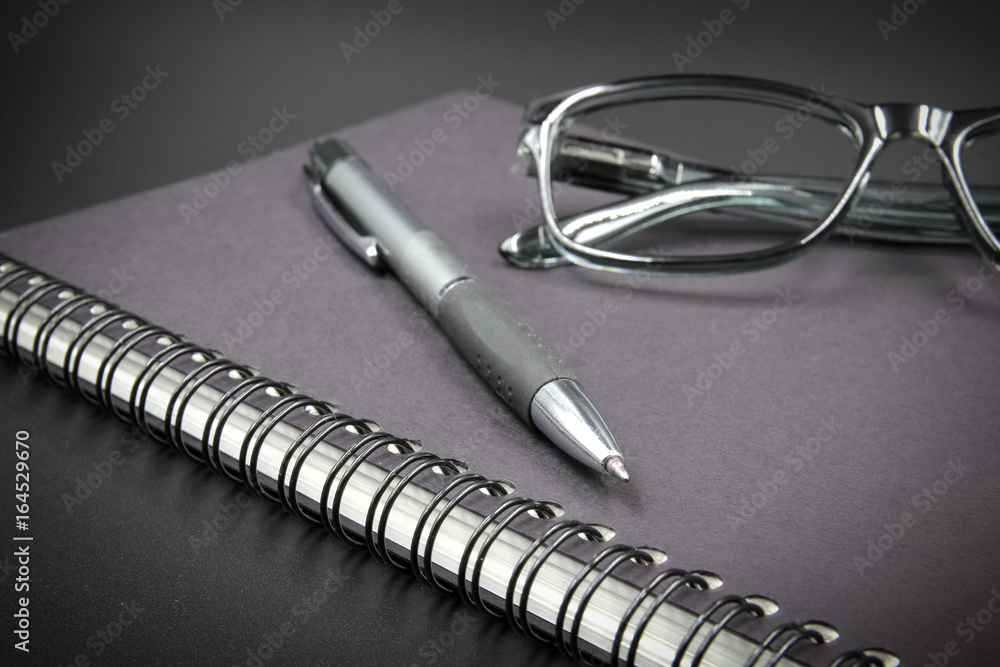 Notebook glasses and pen on black background. Notebook glasses and pen on black background.