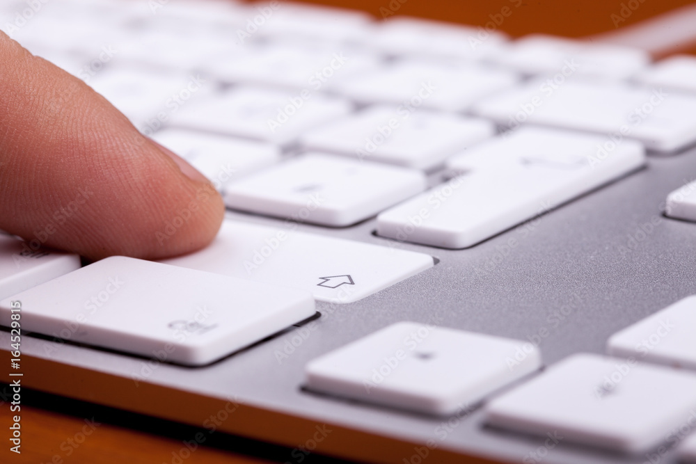 Finger pressing on keyboard key in close up Finger pressing on keyboard key in close up