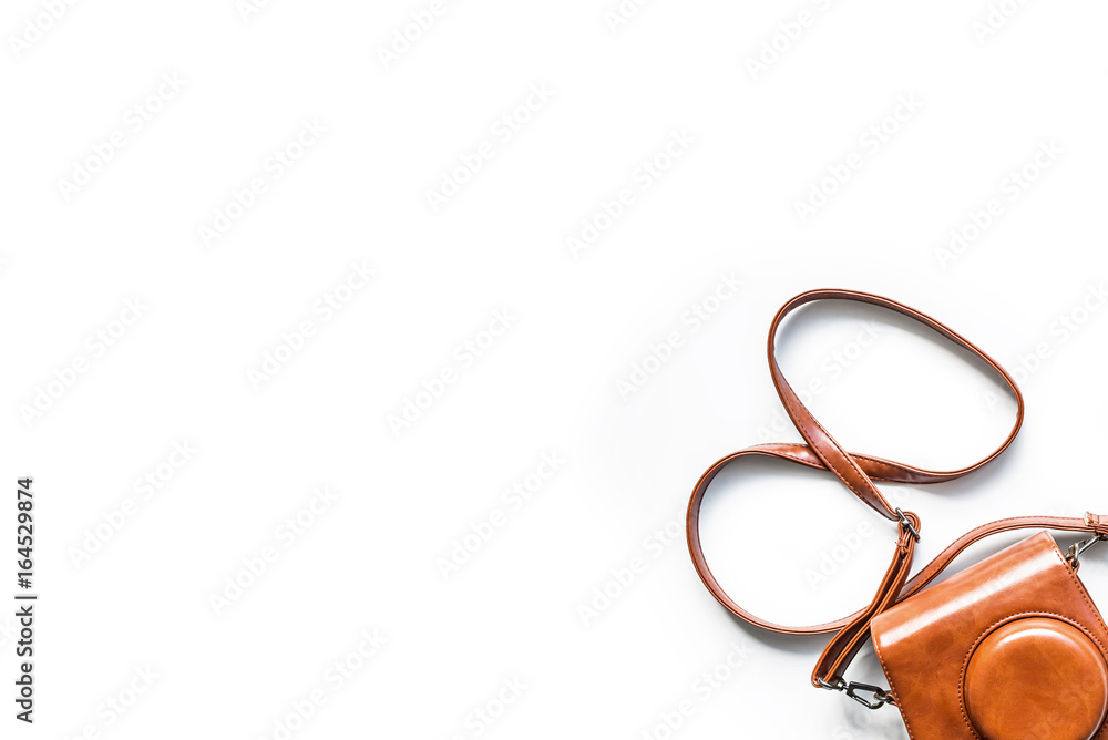 Top view of a small camera in a vintage brown leather case with shoulder strap isolated on a white background