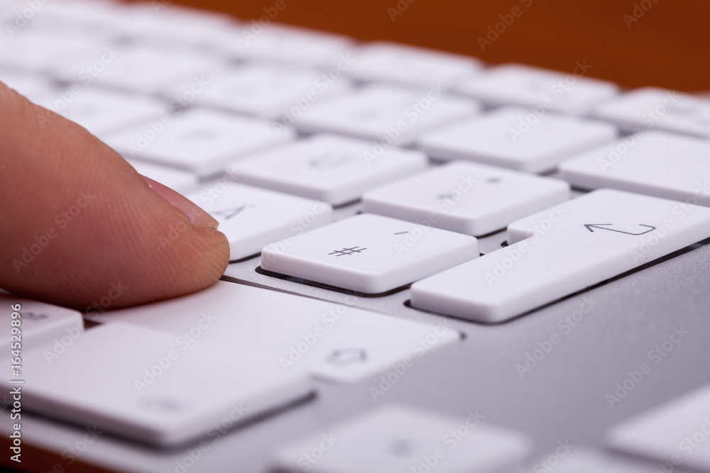 Finger pressing on keyboard key in close up Finger pressing on keyboard key in close up