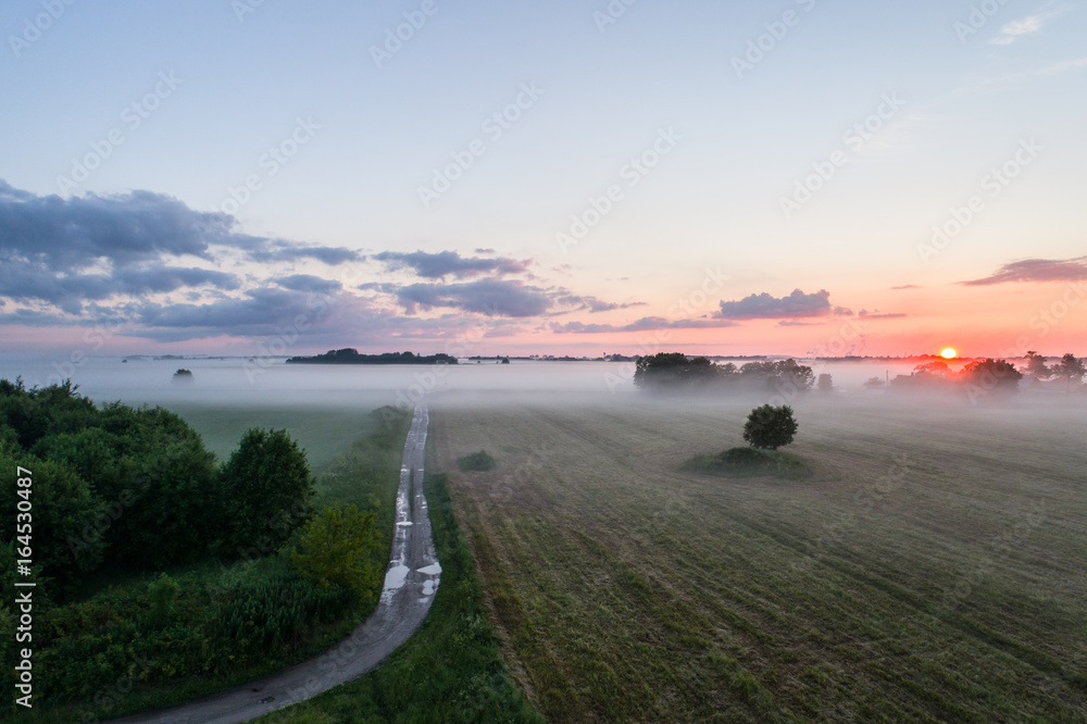 Aerial view of fields with fog at amazing sunset. Summer nature landscape.