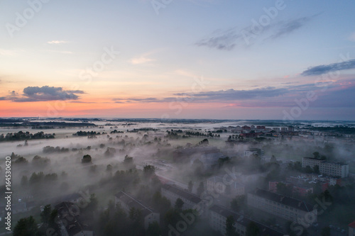 Aerial view of city in fog at amazing sunset. Summer nature landscape.