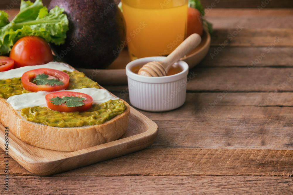 Open sandwich for breakfast or lunch. Healthy sandwich spread with cream cheese, avocado and tomato. Avocado and cream cheese open sandwich style serve with orange juice on rustic wood table. Open sandwich for breakfast or lunch. Healthy sandwich spread with cream cheese, avocado and tomato. Avocado and cream cheese open sandwich style serve with orange juice on rustic wood table.