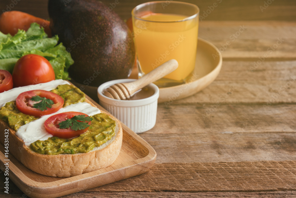 Open sandwich for breakfast or lunch. Healthy sandwich spread with cream cheese, avocado and tomato. Avocado and cream cheese open sandwich style serve with orange juice on rustic wood table. Open sandwich for breakfast or lunch. Healthy sandwich spread with cream cheese, avocado and tomato. Avocado and cream cheese open sandwich style serve with orange juice on rustic wood table.