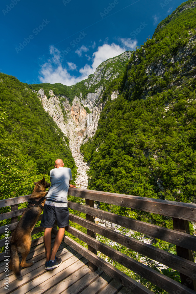 Man and dog looking at Boka waterfall in Slovenia