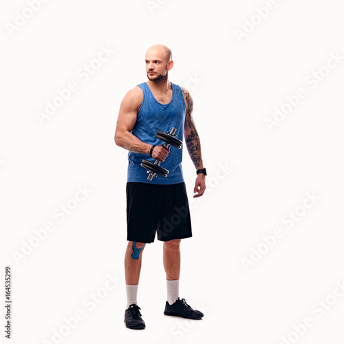 Shaved head male holds dumbbell.