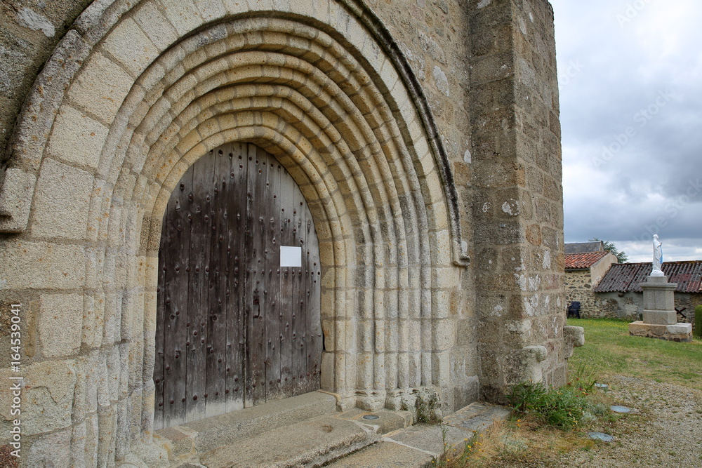 The main entrance to Vieux Pouzauges Church with a statue of Virgin Mary in the background, Pouzauges, Vendee, France
