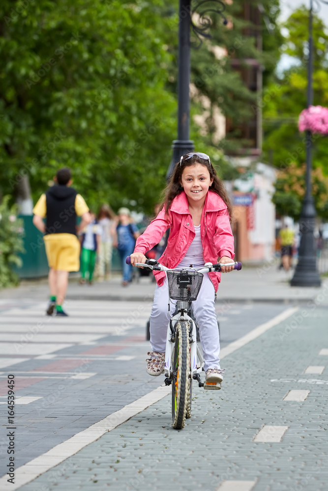 Fototapeta premium Cute kid in safety helmet biking outdoors. Little girl on a red bicycle Healthy preschool children summer activity.