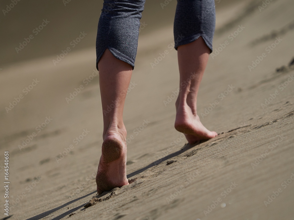 bare feet of young woman jogging/walking on the beach at sunrise