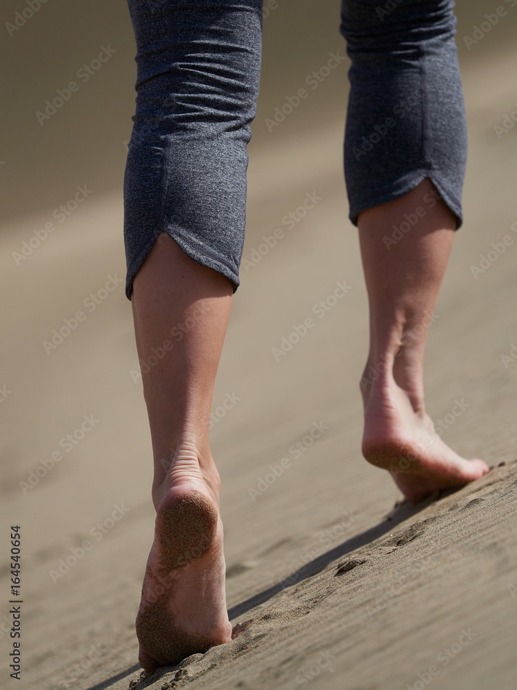 bare feet of young woman jogging/walking on the beach at sunrise