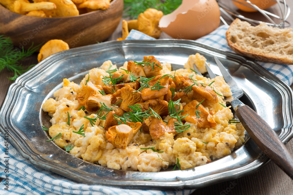 scrambled eggs with chanterelles and fresh dill on a plate, close-up