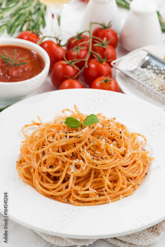 pasta with tomato sauce on a plate and ingredients, vertical
