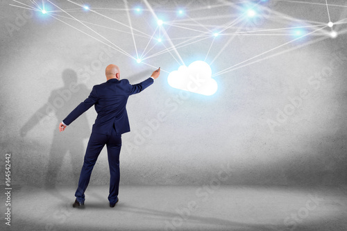 Businessman in front of a wall with a Cloud network with net and connection - Technology concept
