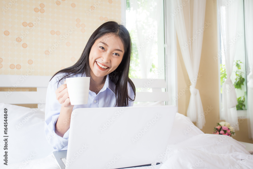 Happy young asian woman holding coffee cup while using laptop with attractive smiling, 20s year old. Happy young asian woman holding coffee cup while using laptop with attractive smiling, 20s year old.
