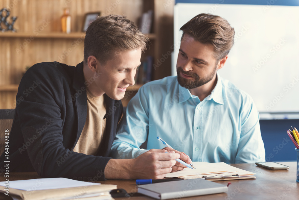 Cheery youthful guys filling job application in office Cheery youthful guys filling job application in office