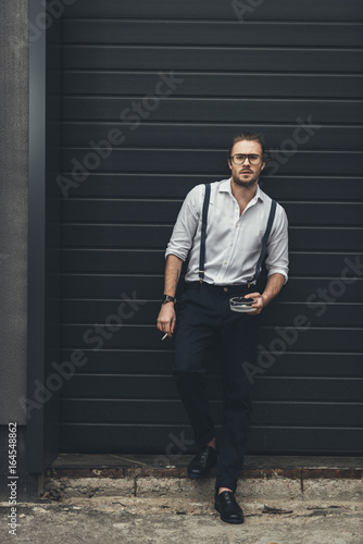 Stylish confident man standing with cigarette and ashtray © LIGHTFIELD STUDIOS