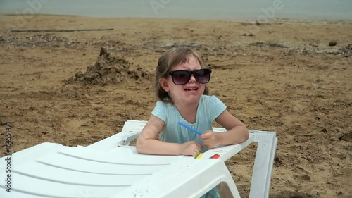 Little girl is crying on the beach. Her mother comes to her and helps to do something. photo