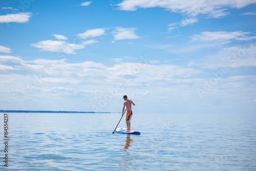 A young guy is floating on a sup board against the blue sky © Анна Ковальчук