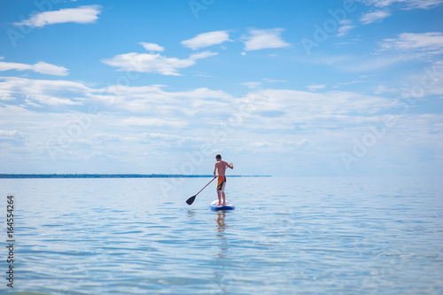 A young guy is floating on a sup board against the blue sky © Анна Ковальчук