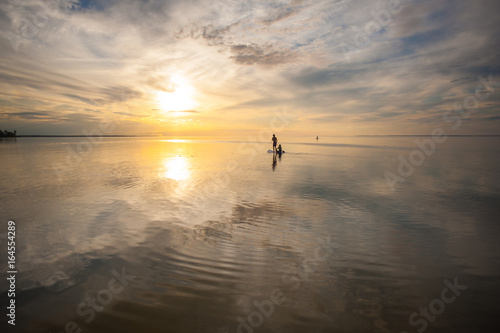 A loving couple is swimming on a sup board in the sea or the ocean against a sunset background © Анна Ковальчук