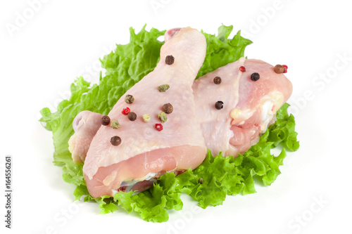 Two raw chicken drumsticks with lettuce leaf isolated on white background