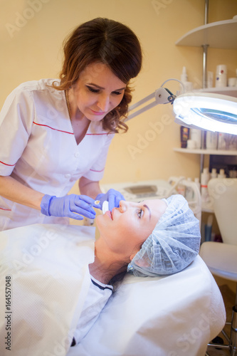 doctor cosmetologist makes injection syringe on the face