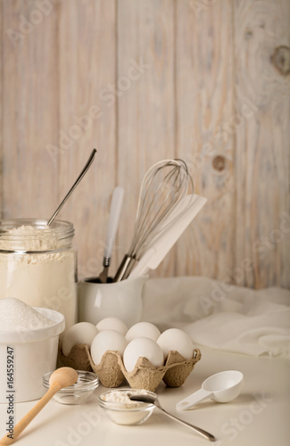 Kitchen utensils and tools for homemade baking on a light wooden background.