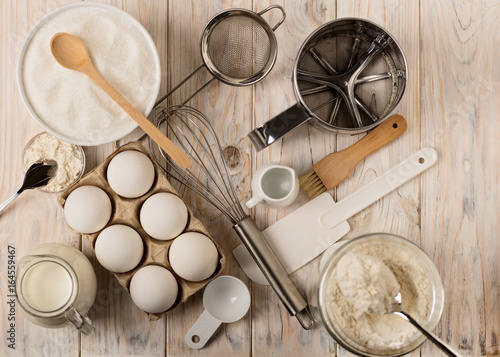 Kitchen utensils and tools for homemade baking on a light wooden background.