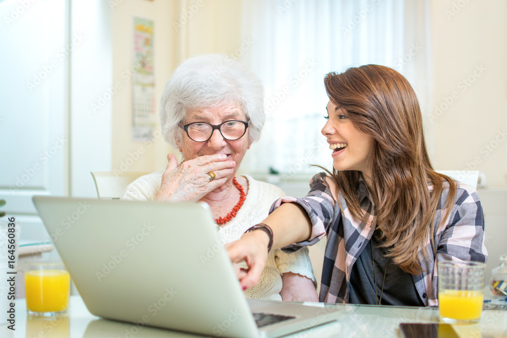 Granddaughter showing something on laptop to her grandmother. Granddaughter showing something on laptop to her grandmother.