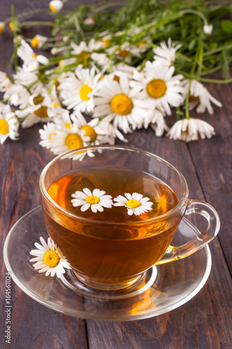 Herbal tea with fresh chamomile flowers on black wooden background