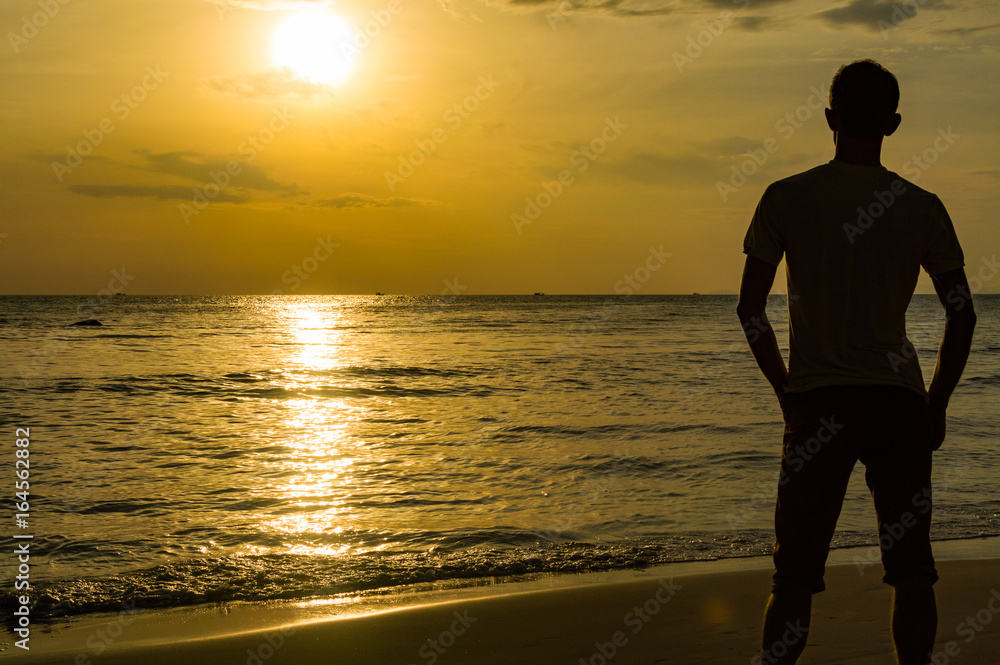 Silhouette of young man on the beach in golden sunset