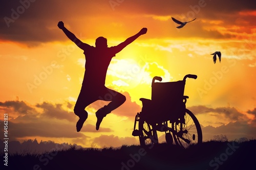 A miracle happened. Disabled handicapped man is healthy again. He is happy and jumping at sunset.