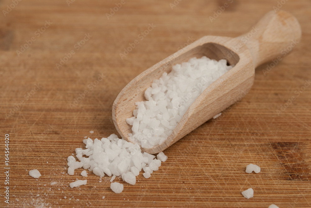 Thick sea salt on a wooden spoon for spices - obrazy, fototapety, plakaty 
