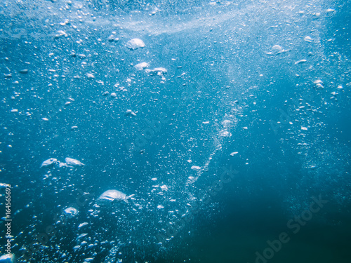 Underwater turquoise texture in ocean. Bubbles in sea. 