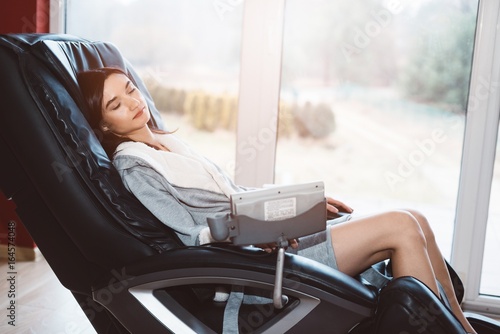 Young woman relaxing on the massaging chair photo