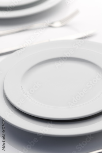 Empty white plates on white table.