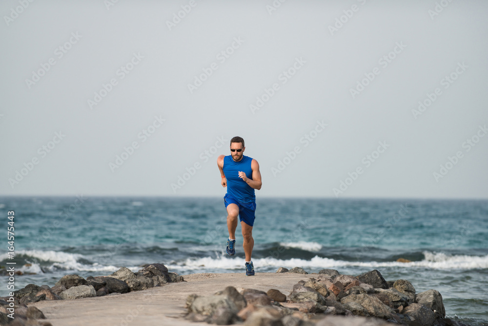 Runner athlete boy jogging training at beautiful beach of ocean
